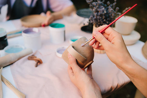 istock Artisan paints a ceramic cup with soft blue paint, capturing the detailed process of pottery decoration and handcrafted ceramic design. Girl is painting ceramic cup with blue paint at a table. 2236805256