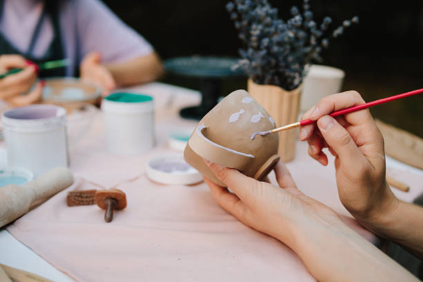 istock Ceramic painting of mug with fish pattern using brush strokes. Artist paints delicate purple fish on a handmade clay mug. Painting ceramic mug with purple fish using brush and paint. 2236805257