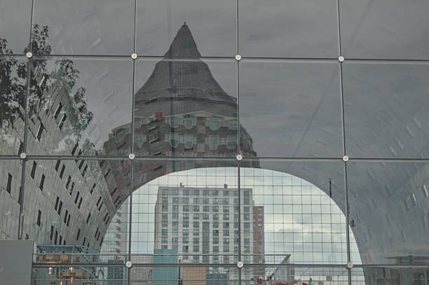 Reflection of iconic Pencil Building and city skyline in the glass facade of Markthal, Rotterdam, Netherlands. Modern urban architecture and contemporary cityscape design.