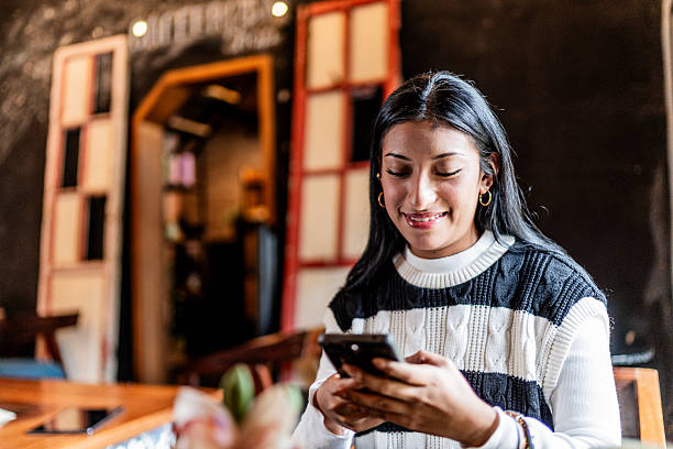 istock Young woman using mobile phone at coffee shop 2236807845