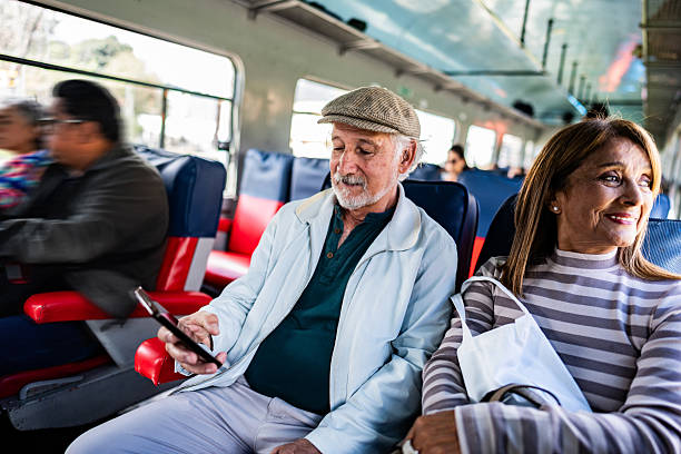 istock Senior man using mobile phone while traveling alongside his wife on the La Sabana train 2236820554