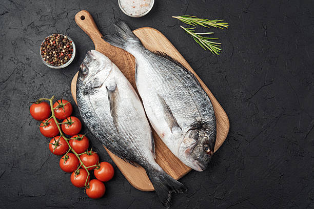 istock Fresh raw dorado fish with tomatoes spices and salt on dark background 2236823662