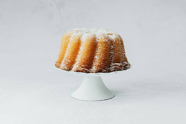 istock Golden bundt cake on white stand with white stone background 2236823710