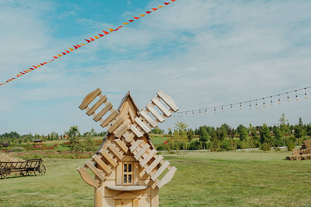 Wooden windmill decoration on grassy field with festive flags and string lights