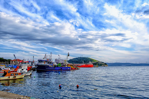 Erdek, Turkey - February 8, 2024 : Erdek Town harbor with ships at sunset with amazing sky