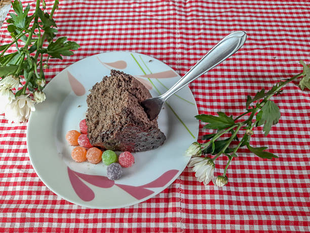 Chocolate cake with jelly candies on a white plate on a red tablecloth