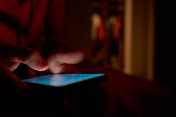 istock Man using smartphone in dark room with glowing screen 2236841600