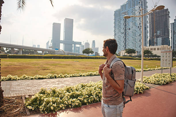 istock Man with backpack exploring dubai city park looking at modern buildings 2236841850