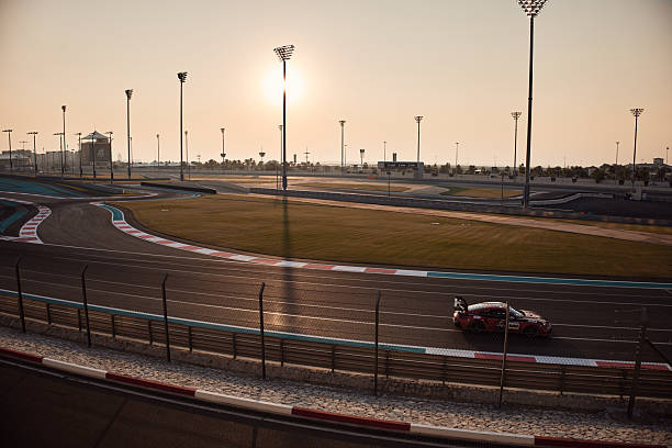 Race car driving fast on a professional racetrack under the warm evening sun
