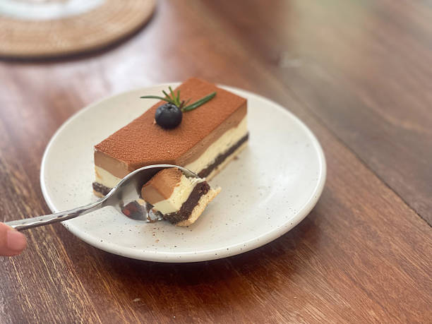 A spoon cutting through a slice of triple layer chocolate cake