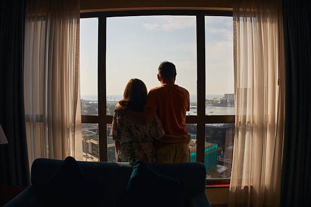 istock Couple embracing by window looking at city view 2236843906