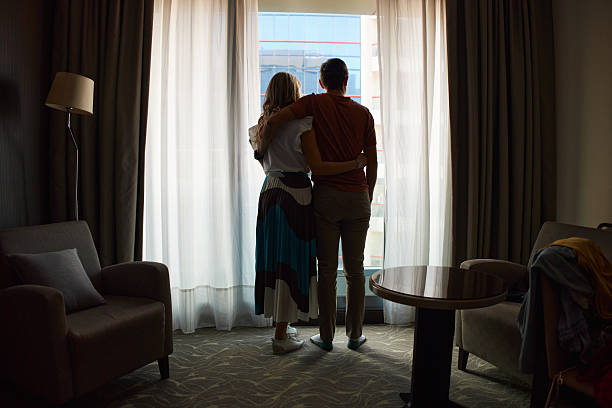 Couple embracing looking out hotel window together