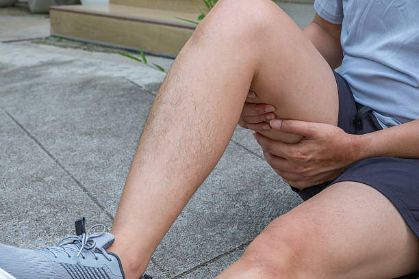istock Asian male athlete seated on concrete, clutching hamstring in sudden post-workout pain. 2236844099