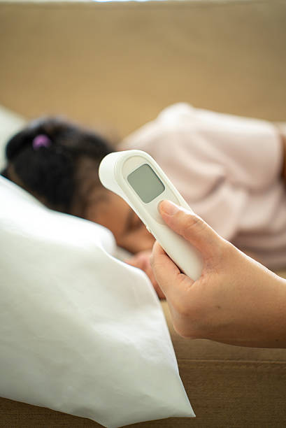 istock Vertical shot selective focus at digital infrared thermometer for checking temperature of sick child’s fever lying on bed, parent caring for child health insurance support and family medical coverage. 2236845110