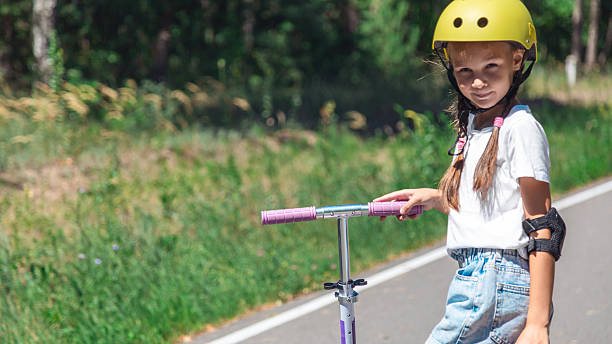 istock Happy child riding scooter in summer with helmet 2236848700
