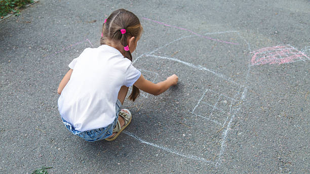 istock little girl drawing with chalk on the asphalt 2236849111