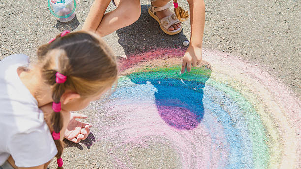 istock Girls drawing rainbow on sidewalk with chalk 2236849175