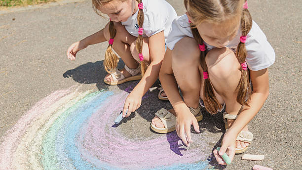 istock Girls drawing rainbow on sidewalk with chalk 2236849334