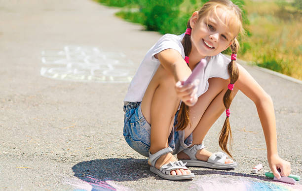 istock Cute girl drawing colored chalk on the asphalt on summer sunny day. Creative development of children. Sidewalk chalk games for kids 2236849336