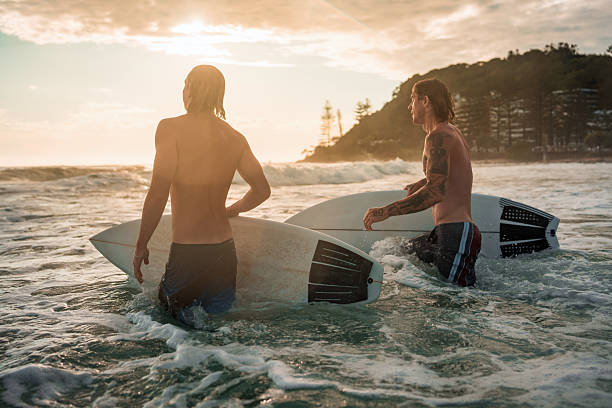 istock Caucasian Male Surfers Joyfully Riding Sunrise Waves 2236849496