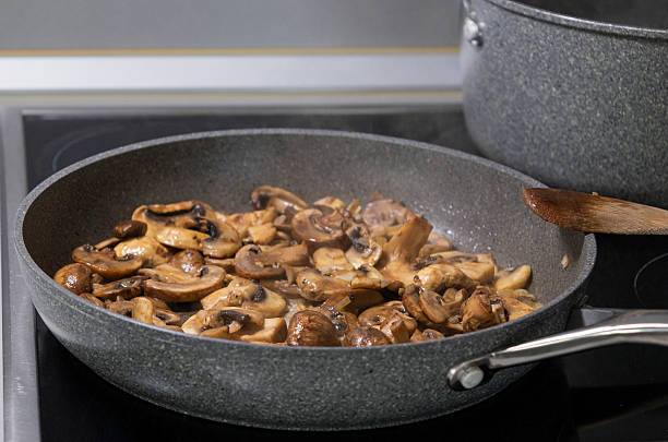 sliced mushrooms and onions sizzling in a hot pan