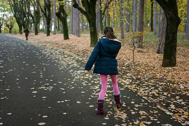 Rear view of two girls walking in the forest during autumn day
