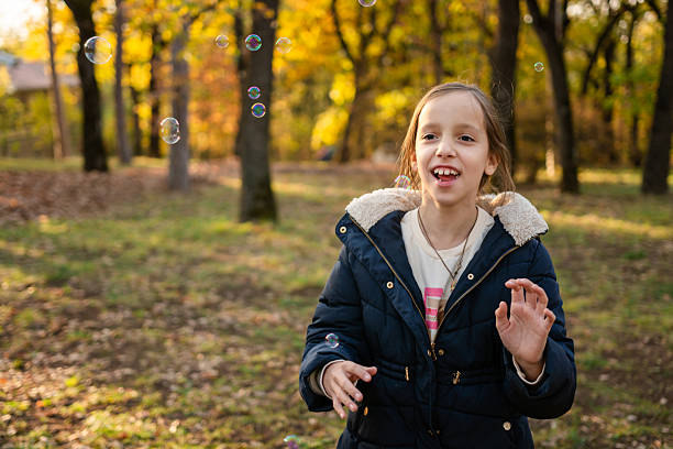 Beautiful little girl catches soap bubbles in a field with lavender