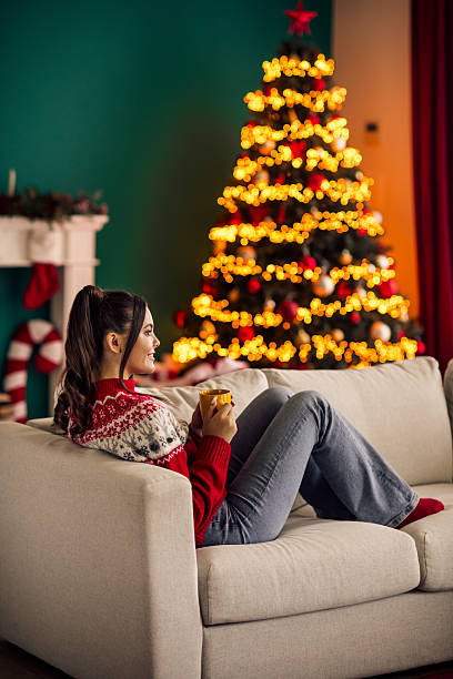 istock Young woman enjoying a cozy Christmas interior with a decorated tree and garlands while sipping a warm holiday drink 2236852795