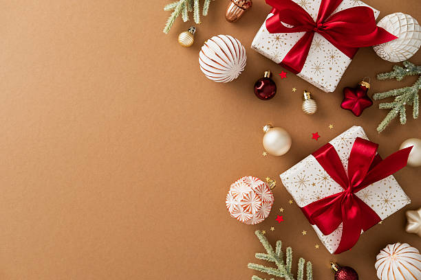 istock Christmas composition with white gift boxes, red ribbons, pine branches, and colorful ornaments on brown background. Flat lay, top view, copy space. 2236853032