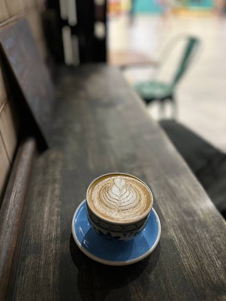 Cup of cappuccino coffee with Rosetta latte art stands on a wooden desk