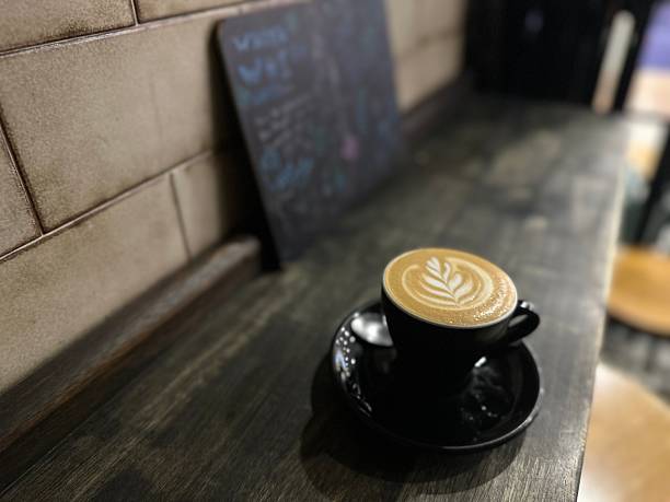 Cup of cappuccino coffee with Rosetta latte art stands on a wooden desk