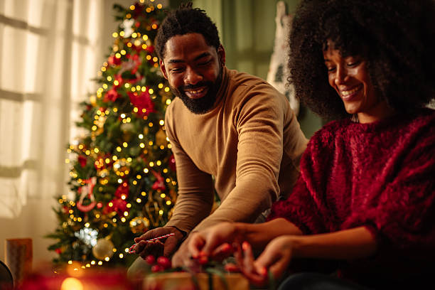 istock Couple wrapping Christmas presents near illuminated tree 2236853727