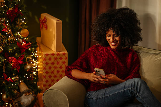 istock Woman using mobile phone near Christmas tree and gifts 2236853741
