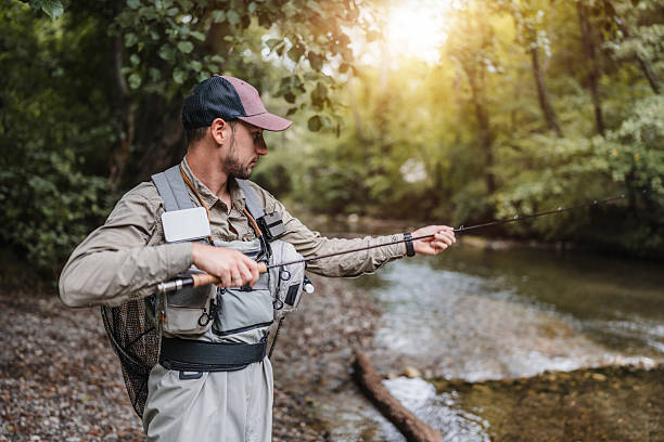 istock Man fly fishing in a shaded forest river 2236854279