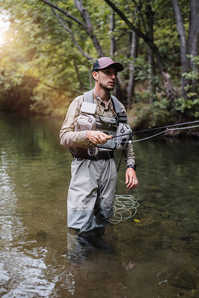 istock Man fly fishing in a shaded forest river 2236854349