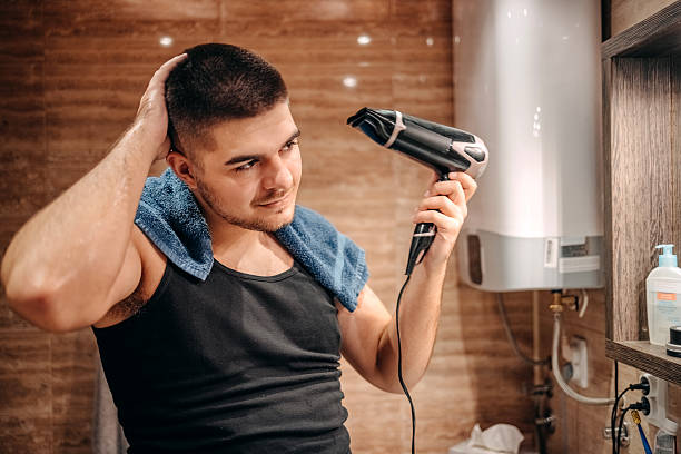 istock Young man at home standing in front of mirror in bathroom and doing morning routine 2236855392