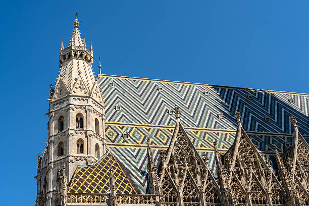 detail of upper part of st. stephens cathedral in vienna city with different roof tiles on sunny summer day and blue sky