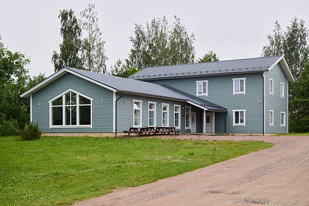 A modern green house, elegantly designed with large windows and surrounded by lush greenery, blending with nature