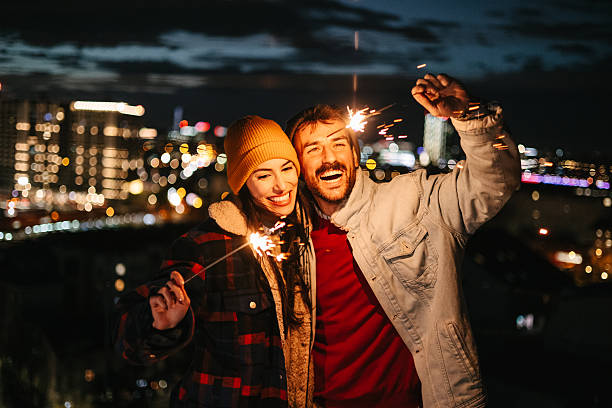 istock Couple holding sparklers with city lights behind 2236870548