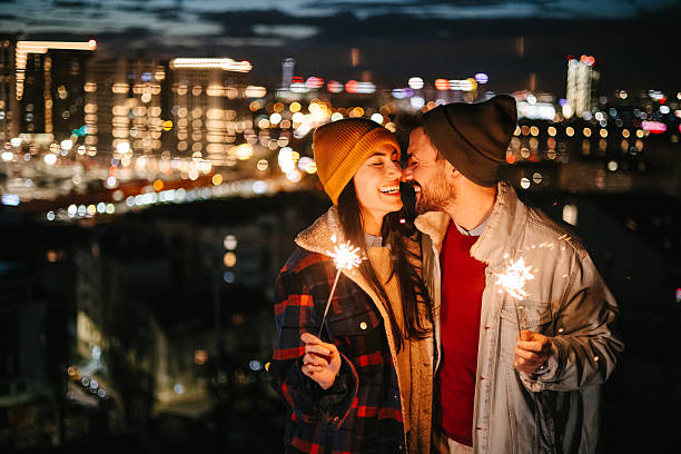 istock Couple holding sparklers with city lights behind 2236870549