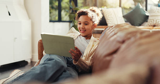 istock Happy, child and browsing on tablet on sofa for educational show, watching cartoon or weekend break. Relax, girl kid or smile with tech in home for streaming subscription, fun app or web scrolling 2236870724
