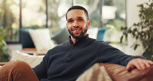 istock Happy, portrait and man on sofa with pride, confidence and relaxing break on weekend getaway. Smile, positive attitude and person on couch for calm holiday, vacation and wellness in living room. 2236870753