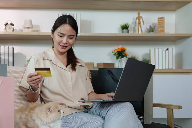 istock Online Shopping. Woman using credit card for e-commerce purchase at home with cat. 2236873056