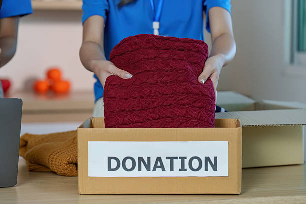 A volunteer engaged in the act of donating a sweater, showcasing community involvement and charitable spirit.