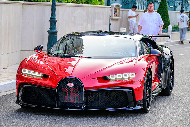 Bugatti Chiron hypercar driving on the street in front of the Casino in Monte Carlo, Monaco, during a summer evening. The Bugatti Chiron is a hypercar renowned for its extraordinary performance, luxury, and engineering precision. Powered by an 8.0-liter quad-turbocharged W16 engine producing 1,479 horsepower, it accelerates from 0–60 mph in under 2.5 seconds and reaches an electronically limited top speed of 261 mph (with special variants exceeding that). Its seven-speed dual-clutch transmission delivers seamless power to all four wheels, while an adaptive suspension ensures stability at extreme speeds.