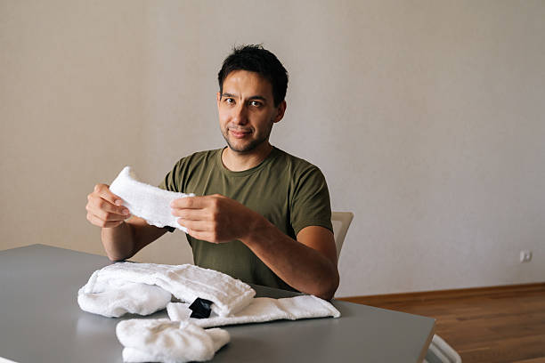 istock Maintenance worker carefully checking microfiber cloths, meticulously preparing cleaning supplies for professional sanitation workflow sitting at table at looking at camera. 2236878527