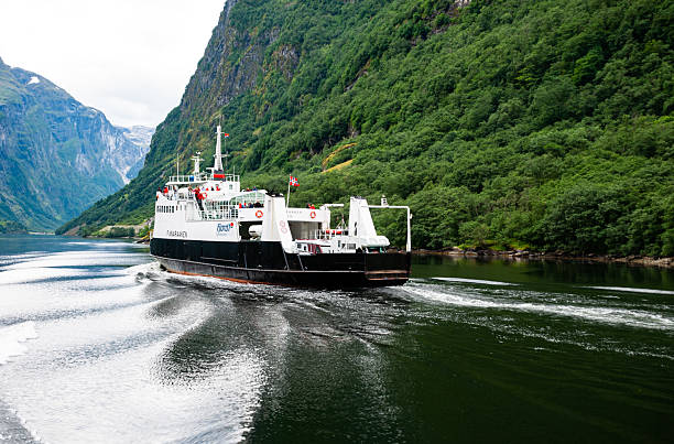 Gudvangen, Norway - August 17, 2013 - Ferry sailing through majestic norwegian fjords with lush greenery.