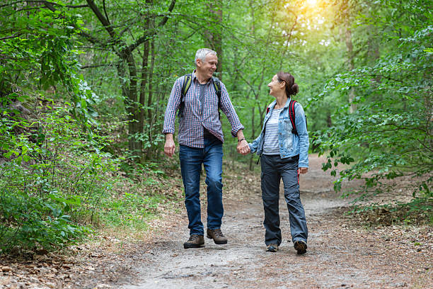 Elderly couple waling together in a green sun lit forest, North Rhine-Westphalia, Germany