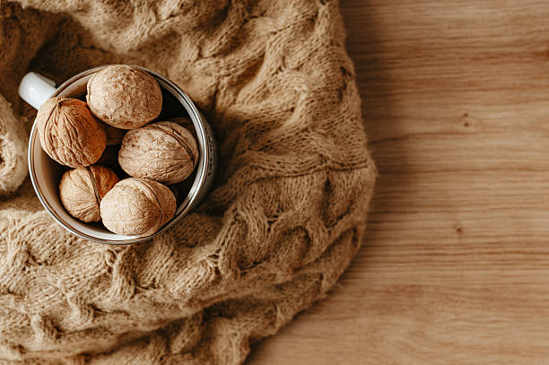 istock A metal mug with whole brown walnuts on a knitted blanket on a wooden table surface with copy space. 2236885159