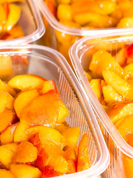 Plastic containers with freshly sliced apricots with sugar ready for freezing